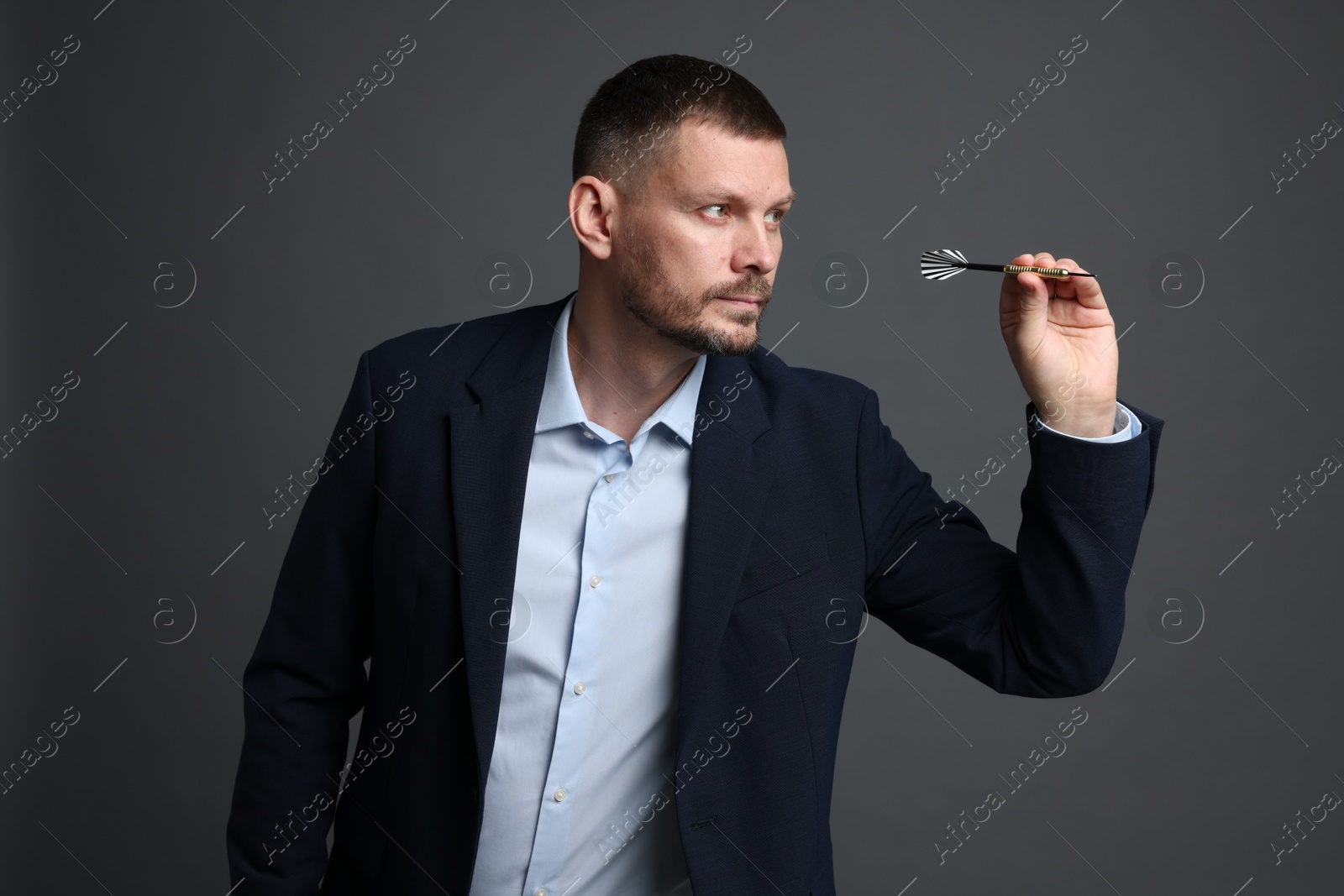 Targeting. Man with dart aiming on grey background Photo of Targeting. Man with dart aiming on grey background