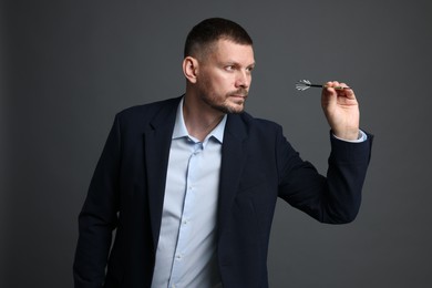Photo of Targeting. Man with dart aiming on grey background