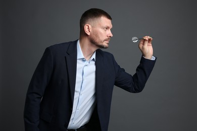 Photo of Targeting. Man with dart aiming on grey background