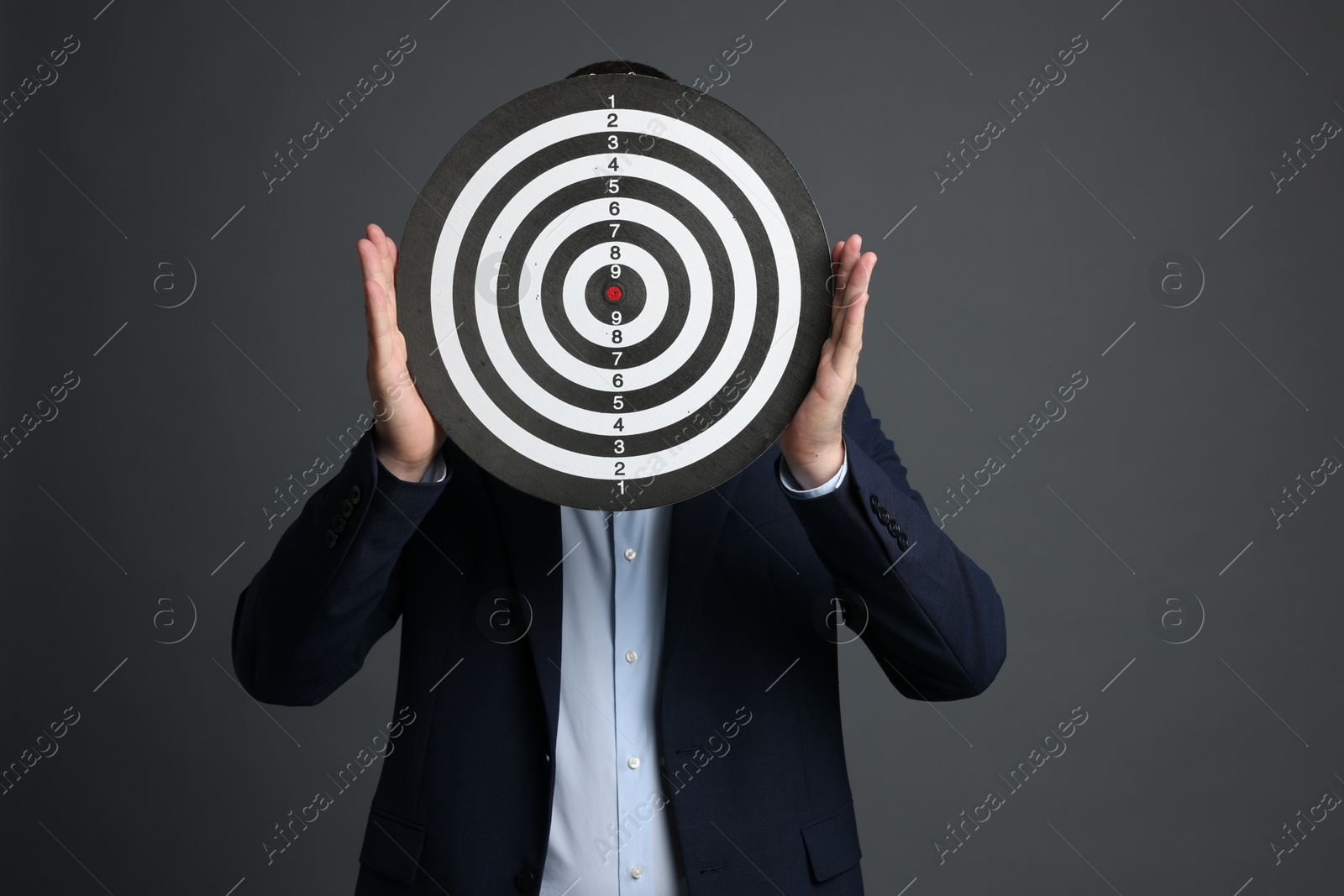 Photo of Targeting. Man with dart board on grey background