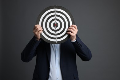 Photo of Targeting. Man with dart board on grey background