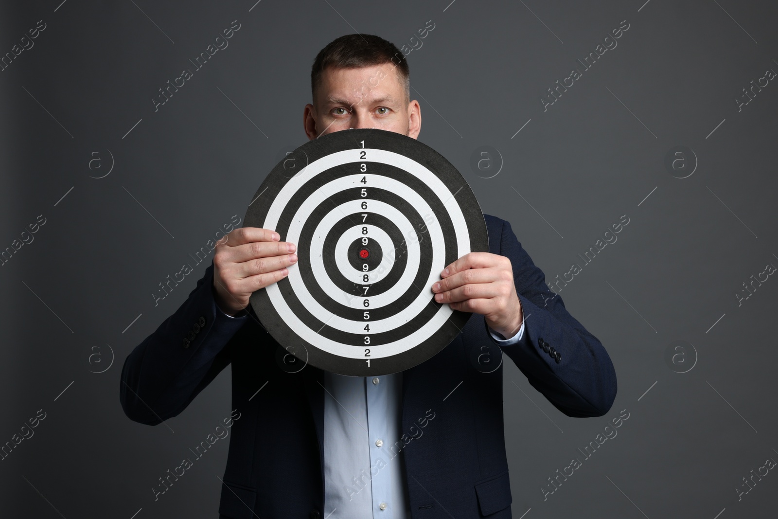 Targeting. Man with dart board on grey background Photo of Targeting. Man with dart board on grey background