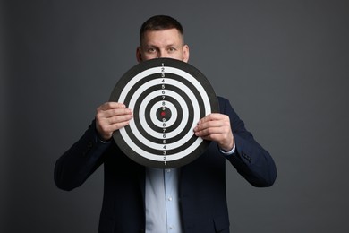 Photo of Targeting. Man with dart board on grey background