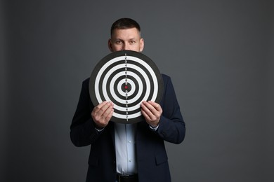 Photo of Targeting. Man with dart board on grey background