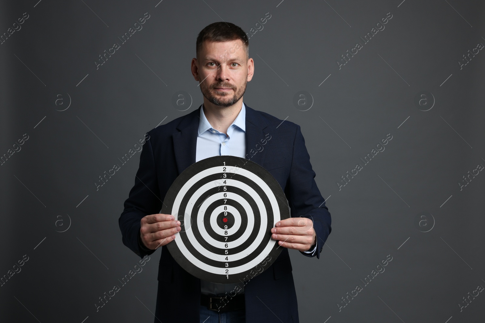 Targeting. Man with dart board on grey background Photo of Targeting. Man with dart board on grey background