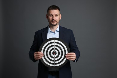 Photo of Targeting. Man with dart board on grey background