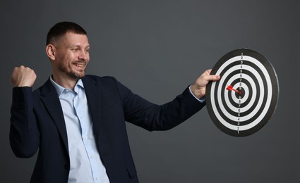 Photo of Targeting. Man with dart board and arrow on grey background