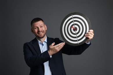 Photo of Targeting. Man with dart board and arrow on grey background