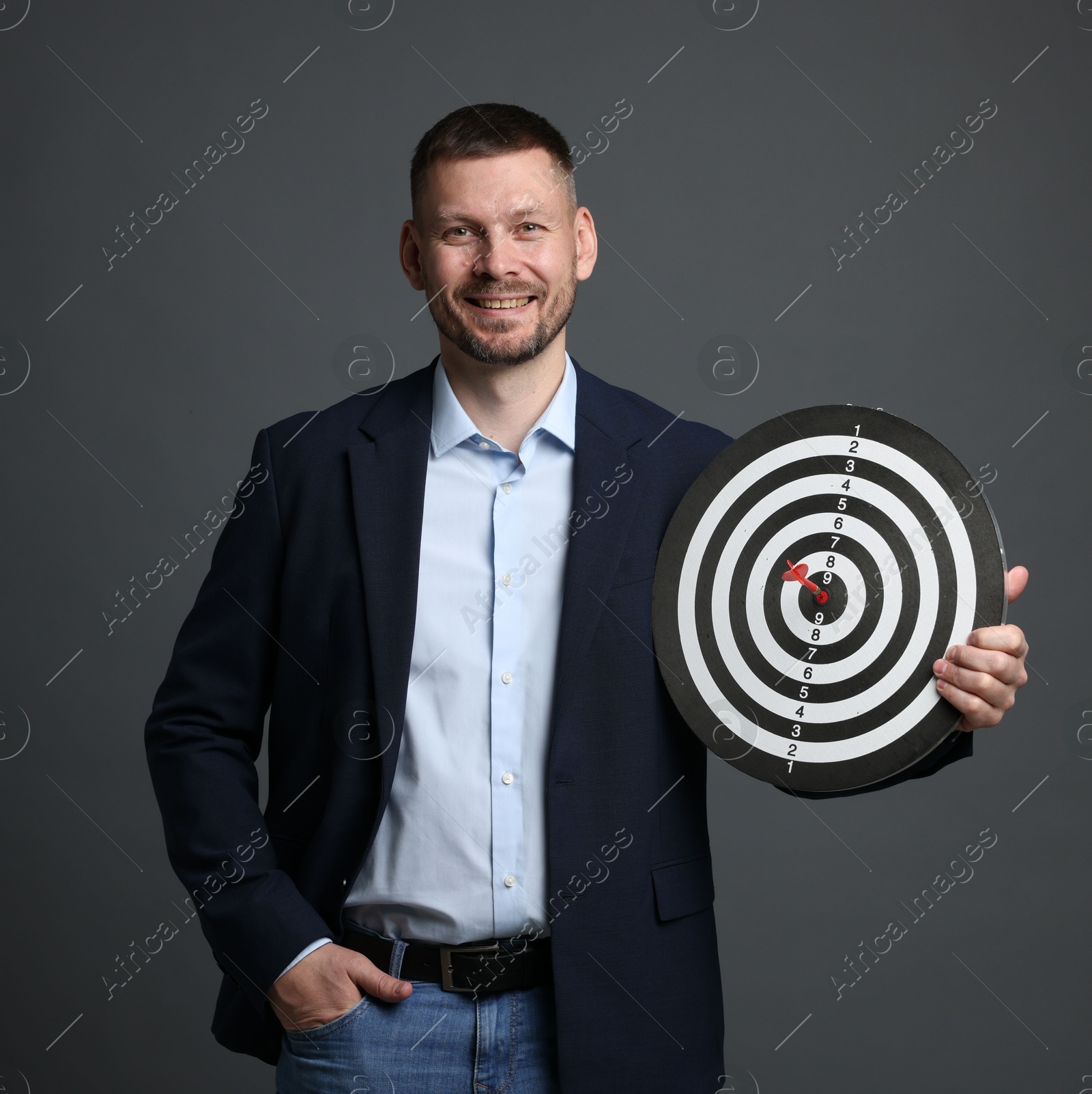 Targeting. Man with dart board and arrow on grey background Photo of Targeting. Man with dart board and arrow on grey background