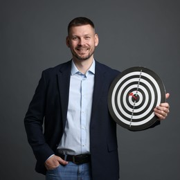 Photo of Targeting. Man with dart board and arrow on grey background