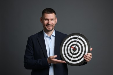 Photo of Targeting. Man with dart board and arrow on grey background
