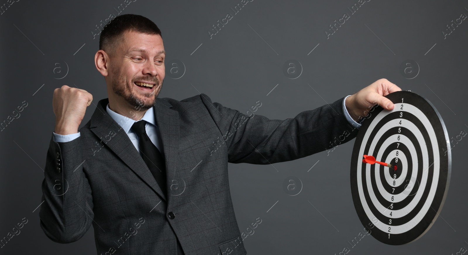 Targeting. Man with dart board and arrow on grey background Photo of Targeting. Man with dart board and arrow on grey background