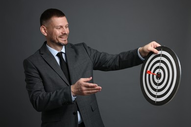 Photo of Targeting. Man with dart board and arrow on grey background