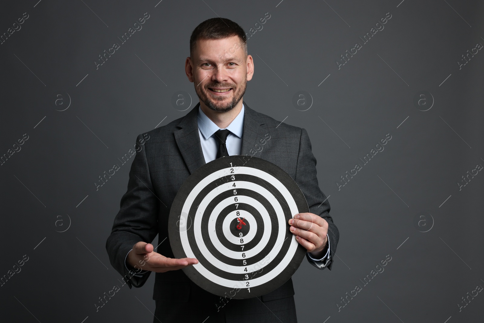 Targeting. Man with dart board and arrow on grey background Photo of Targeting. Man with dart board and arrow on grey background