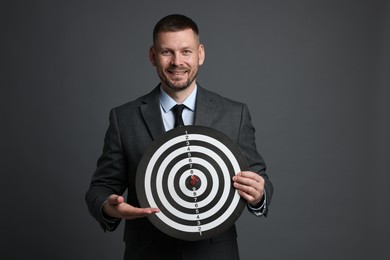 Photo of Targeting. Man with dart board and arrow on grey background