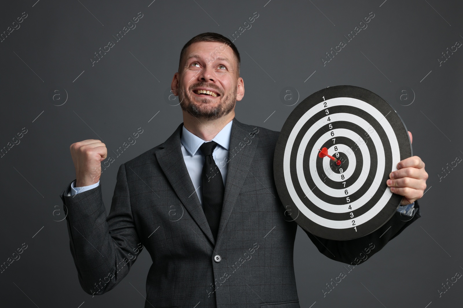 Targeting. Man with dart board and arrow on grey background Photo of Targeting. Man with dart board and arrow on grey background