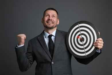 Photo of Targeting. Man with dart board and arrow on grey background