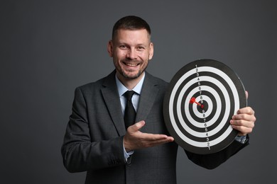 Photo of Targeting. Man with dart board and arrow on grey background