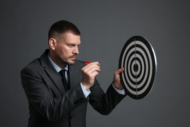 Photo of Targeting. Man with dart board and arrow on grey background