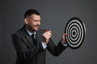 Photo of Targeting. Man with dart board and arrow on grey background