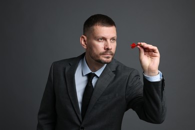 Photo of Targeting. Man with dart aiming on grey background