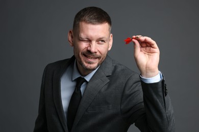 Photo of Targeting. Man with dart aiming on grey background