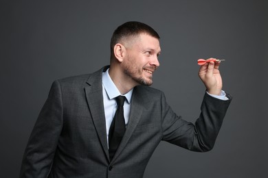 Photo of Targeting. Man with dart aiming on grey background