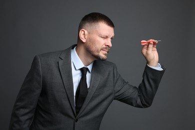 Photo of Targeting. Man with dart aiming on grey background