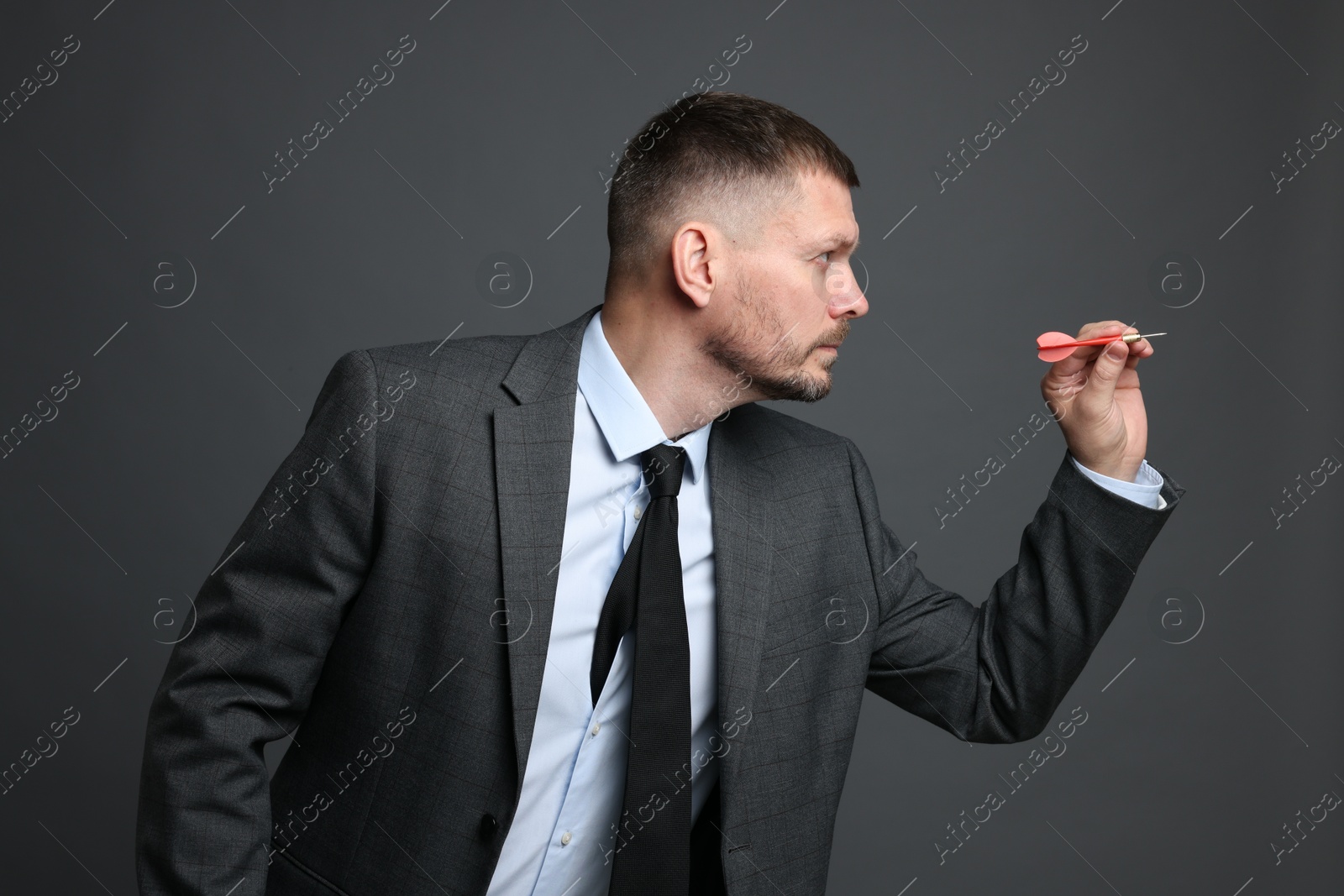 Targeting. Man with dart aiming on grey background Photo of Targeting. Man with dart aiming on grey background