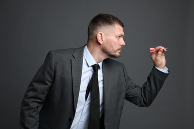 Photo of Targeting. Man with dart aiming on grey background