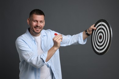 Photo of Targeting. Man with dart board and arrow on grey background