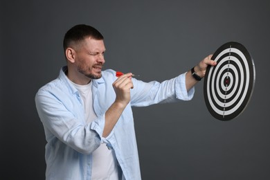 Photo of Targeting. Man with dart board and arrow on grey background