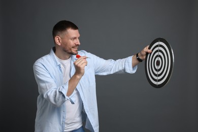 Photo of Targeting. Man with dart board and arrow on grey background