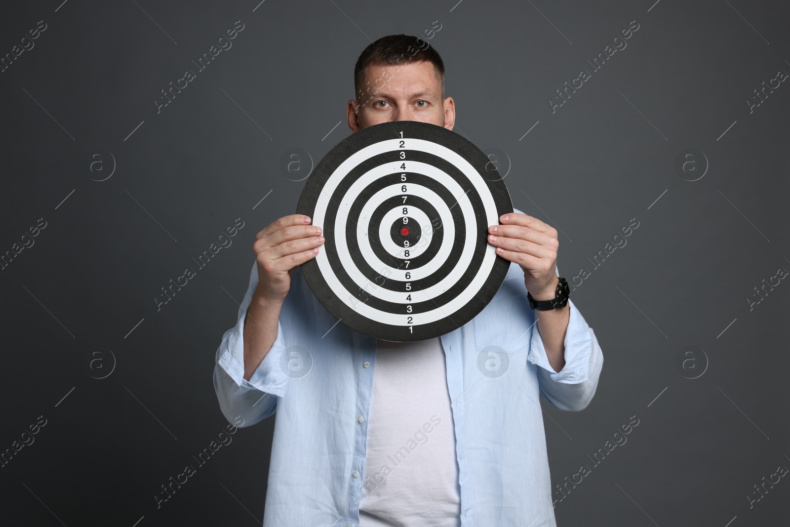 Targeting. Man with dart board on grey background Photo of Targeting. Man with dart board on grey background