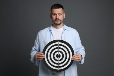 Photo of Targeting. Man with dart board on grey background