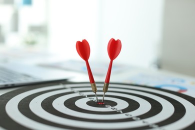 Photo of Targeting. Dart board with arrows on table indoors, closeup