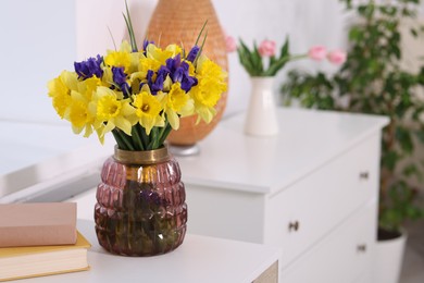 Photo of Bouquet of beautiful flowers in vase on desk indoors