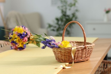 Photo of Wicker basket with beautiful flowers on table indoors