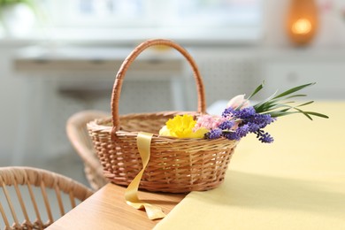 Photo of Wicker basket with beautiful flowers on table indoors
