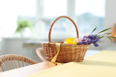 Photo of Wicker basket with beautiful flowers on table indoors