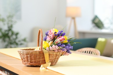 Photo of Wicker basket with beautiful flowers on wooden table indoors