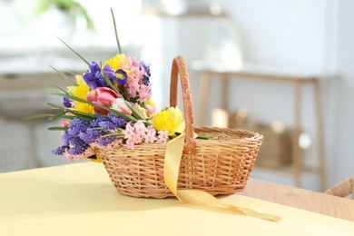 Photo of Wicker basket with beautiful flowers on table indoors