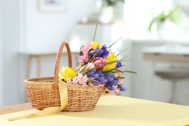 Photo of Wicker basket with beautiful flowers on table indoors