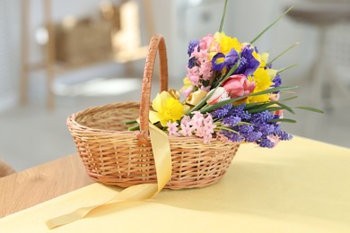Photo of Wicker basket with beautiful flowers on table indoors