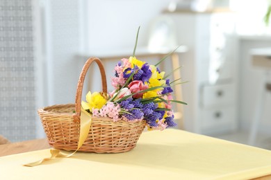 Photo of Wicker basket with beautiful flowers on table indoors