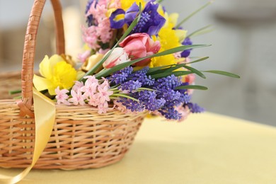 Photo of Wicker basket with beautiful flowers on table indoors, closeup