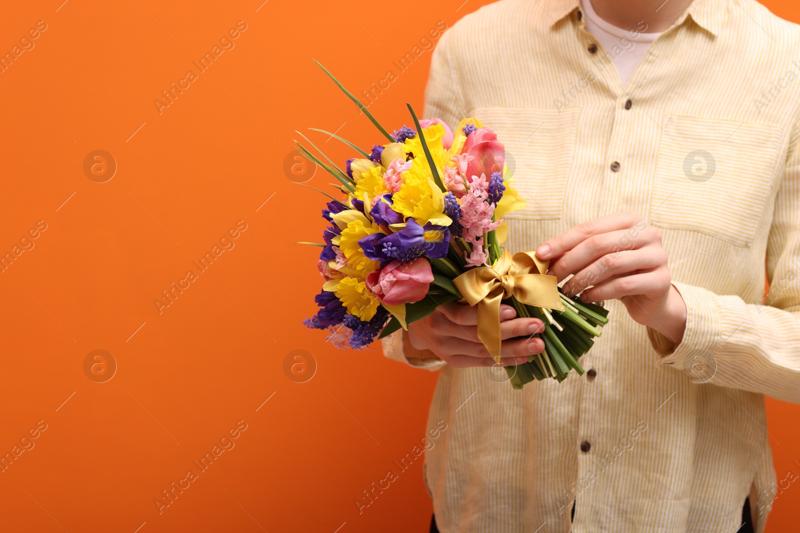 Woman with bouquet of beautiful flowers on orange background, closeup. Space for text Photo of Woman with bouquet of beautiful flowers on orange background, closeup. Space for text