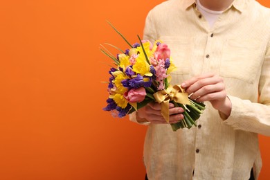 Photo of Woman with bouquet of beautiful flowers on orange background, closeup. Space for text