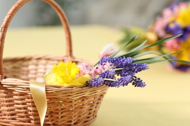 Photo of Wicker basket with beautiful flowers on table indoors, closeup