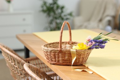 Photo of Wicker basket with beautiful flowers on table indoors